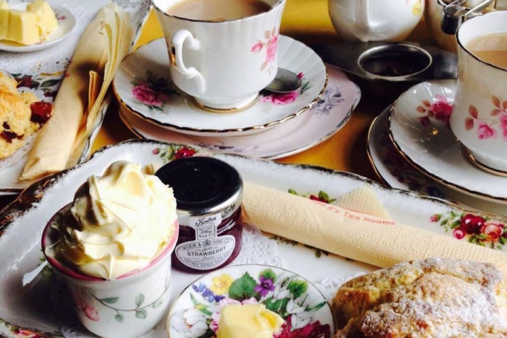 Cream tea, with jam, scone, butter on a small tea plate and tea cup