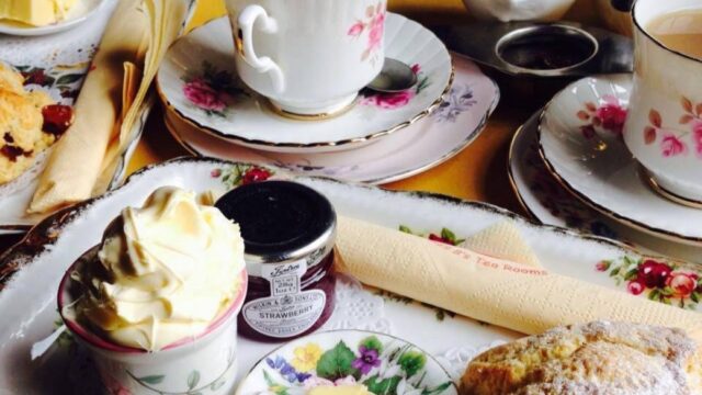 Cream tea, with jam, scone, butter on a small tea plate and tea cup