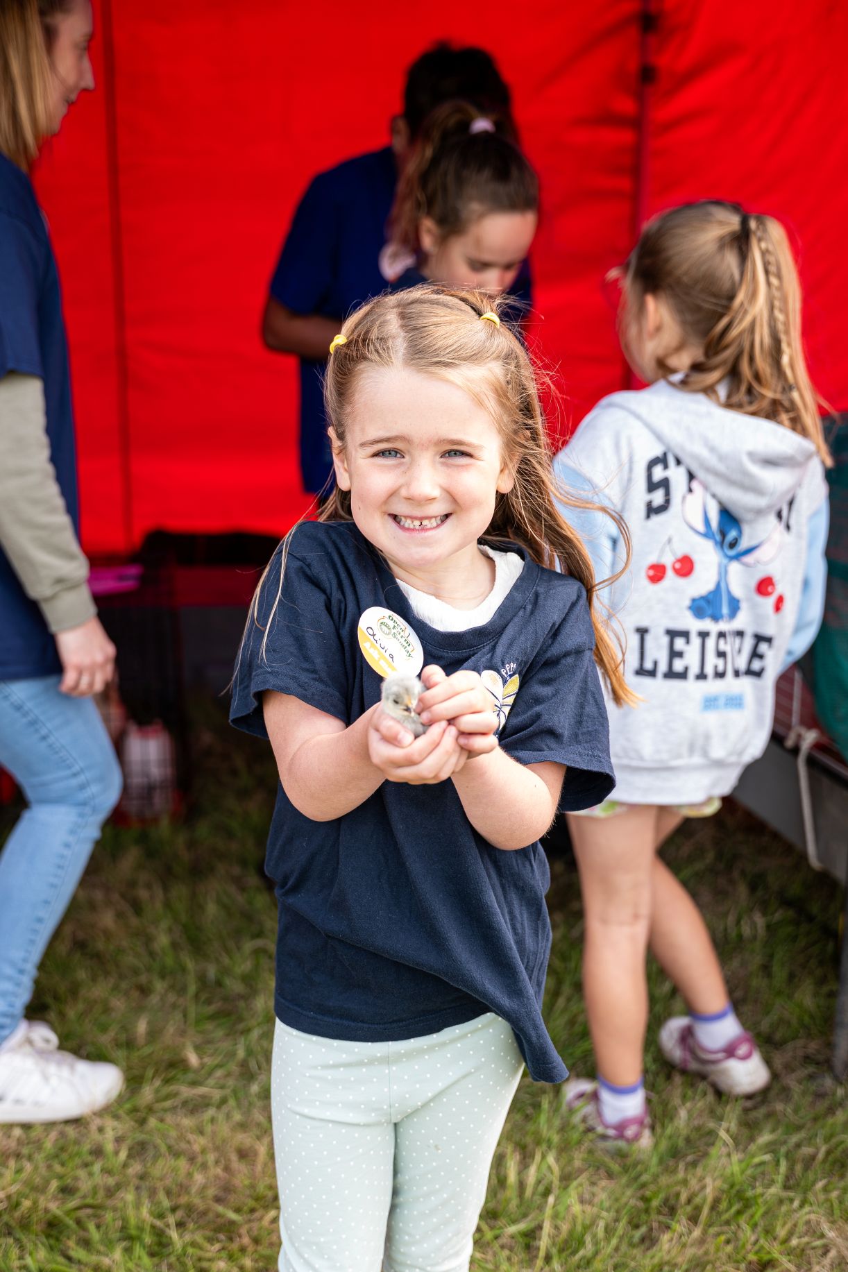 Young girl in a blue t-shirt holding a baby chic