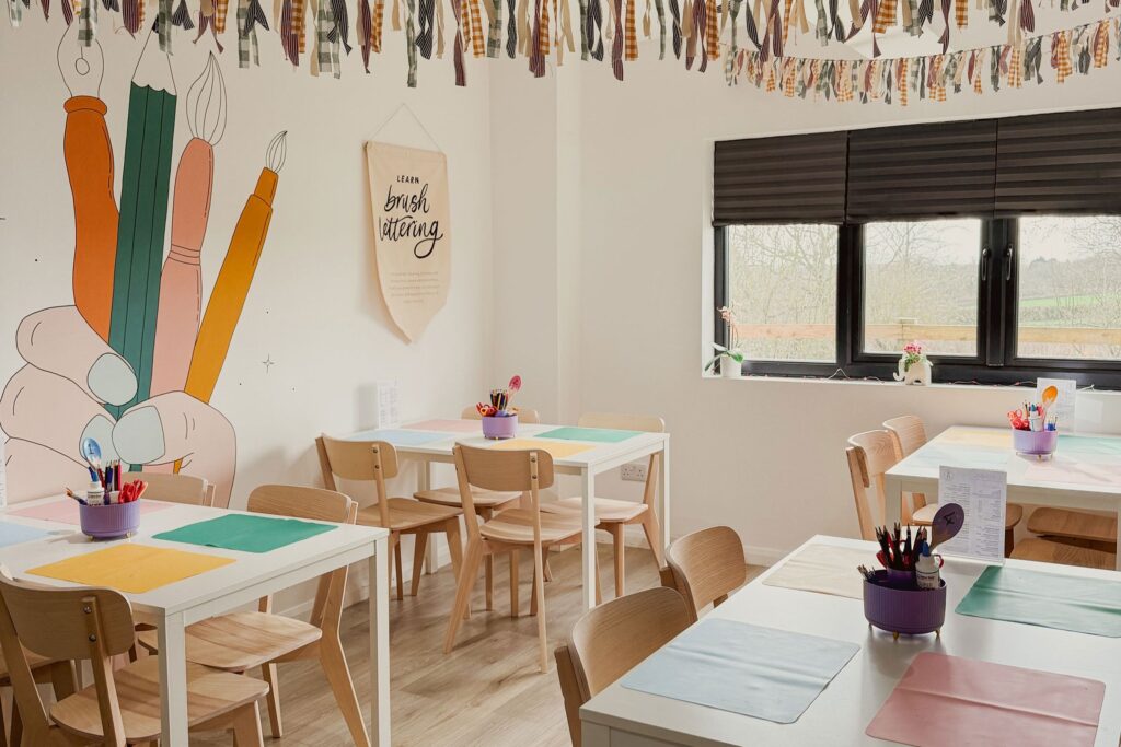 Creative workshop space at The Makers Millhouse with craft tables, art supplies and colourful wall illustrations.