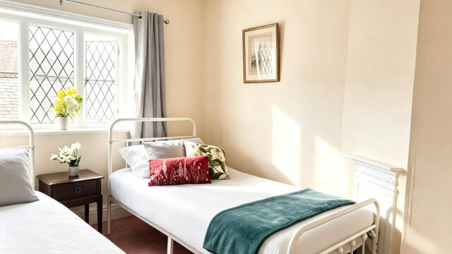 Light twin bedroom with two single beds and window.