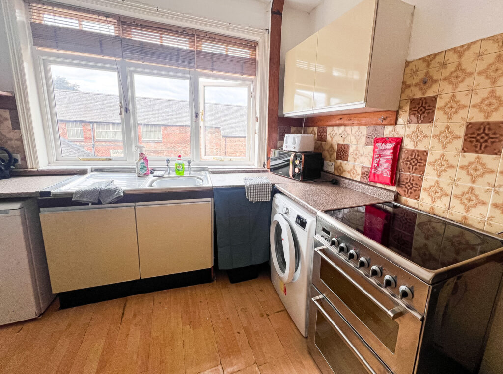 Modern kitchen with oven, washing machine and large window.