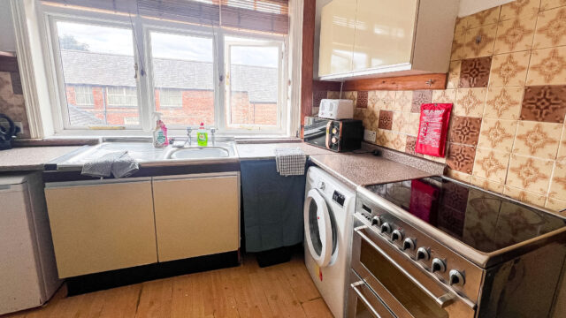 Modern kitchen with oven, washing machine and large window.